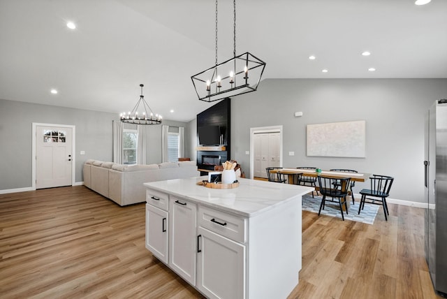 kitchen with vaulted ceiling, light wood-type flooring, a kitchen island, and white cabinetry