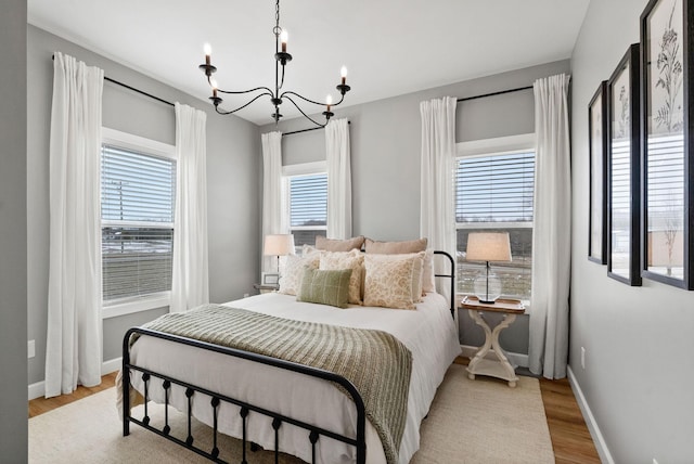 bedroom featuring light wood-type flooring, a notable chandelier, and baseboards