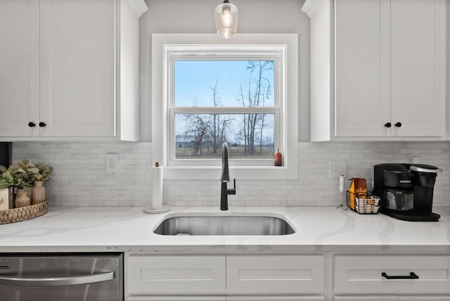 kitchen featuring tasteful backsplash, white cabinets, a sink, and stainless steel dishwasher