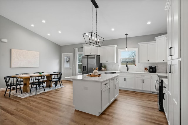 kitchen featuring a kitchen island, stainless steel appliances, light countertops, light wood-style floors, and a sink