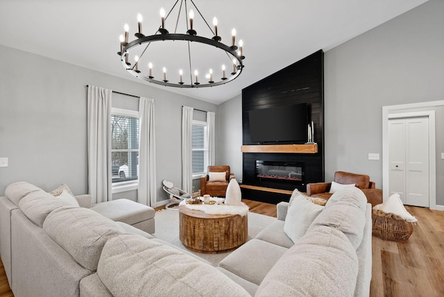 living room featuring vaulted ceiling, a large fireplace, baseboards, and light wood-style floors