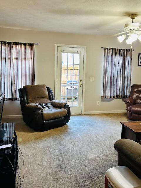 carpeted living room with baseboards and a ceiling fan