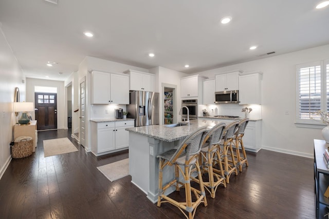 kitchen featuring appliances with stainless steel finishes, visible vents, dark wood finished floors, and light stone counters