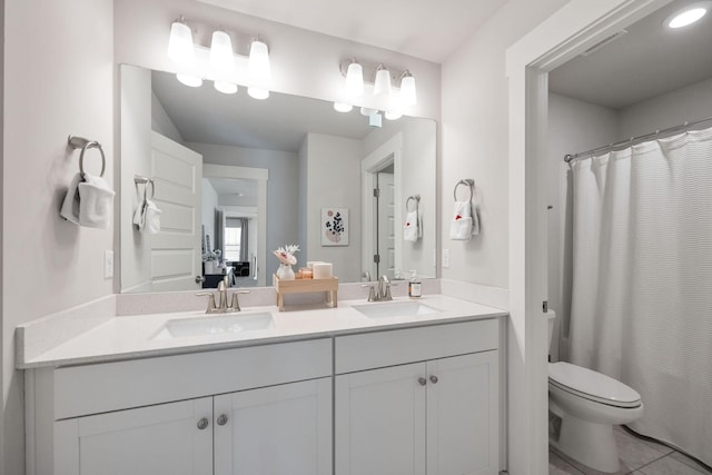 bathroom with tile patterned floors, a sink, toilet, and double vanity