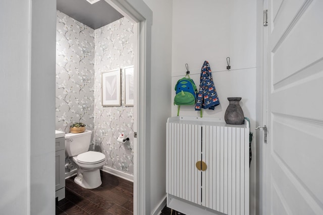 bathroom with wallpapered walls, baseboards, radiator, toilet, and wood finished floors