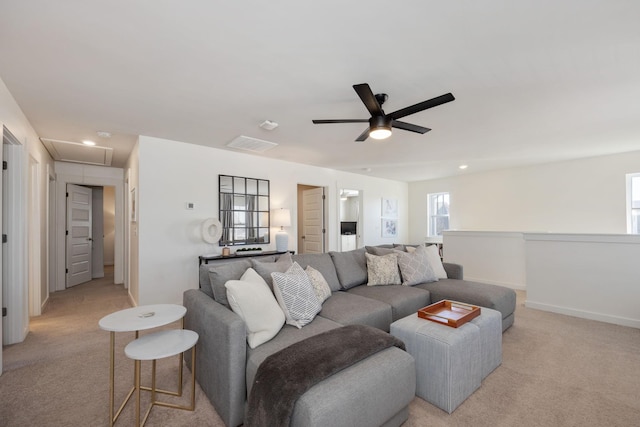 living area featuring attic access, baseboards, a ceiling fan, and light colored carpet