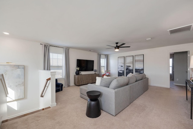 living area with a ceiling fan, light colored carpet, visible vents, and baseboards