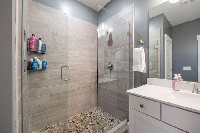 bathroom with a stall shower, visible vents, and vanity