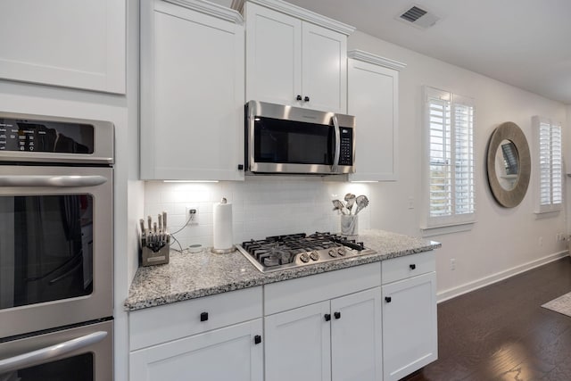 kitchen featuring appliances with stainless steel finishes, visible vents, decorative backsplash, and white cabinetry