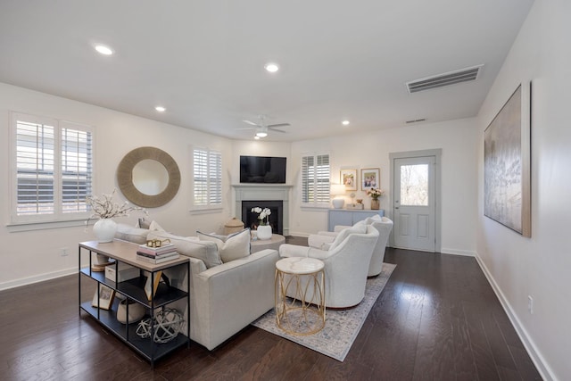 living room featuring a wealth of natural light, dark wood-type flooring, visible vents, and baseboards