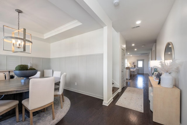 dining space with a wainscoted wall, wood finished floors, visible vents, and crown molding