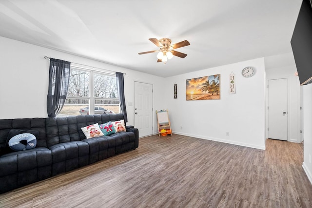 living room featuring wood finished floors, a ceiling fan, and baseboards