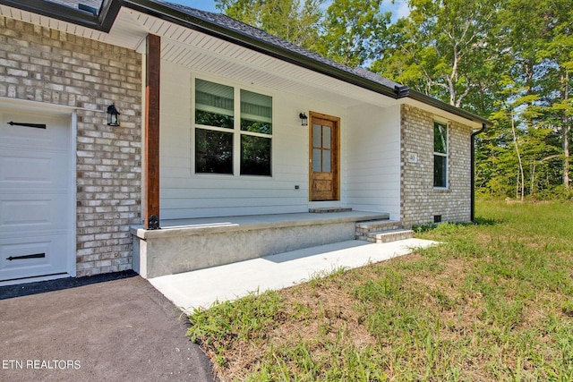 view of exterior entry with brick siding and an attached garage