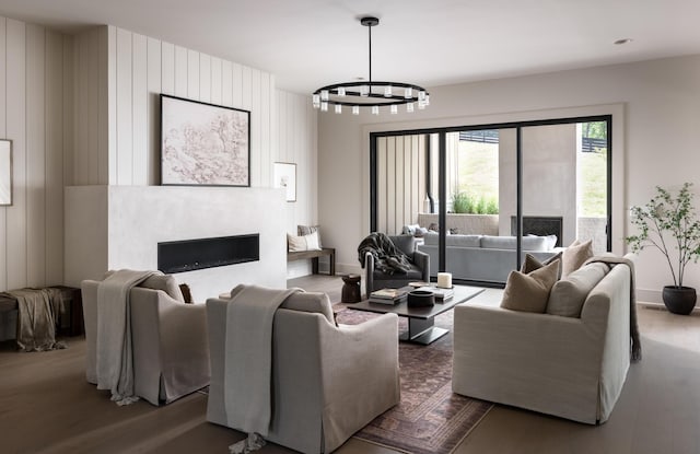 living area with a notable chandelier, a fireplace, baseboards, and wood finished floors