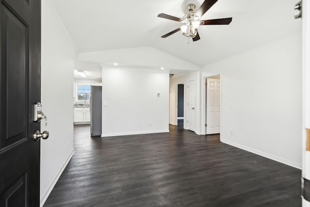 unfurnished room featuring vaulted ceiling, dark wood finished floors, a ceiling fan, and baseboards