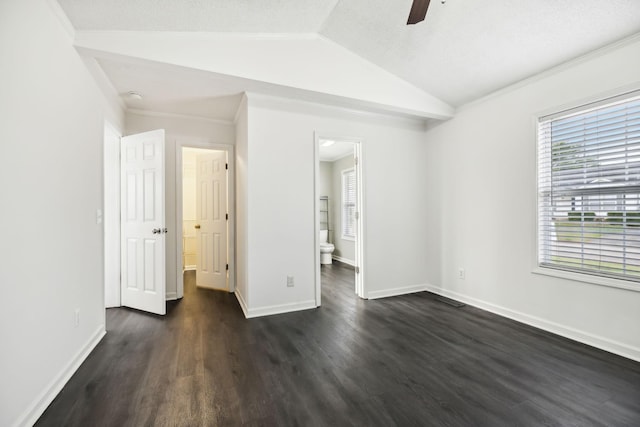 unfurnished bedroom with lofted ceiling, ensuite bathroom, a ceiling fan, baseboards, and dark wood-style floors