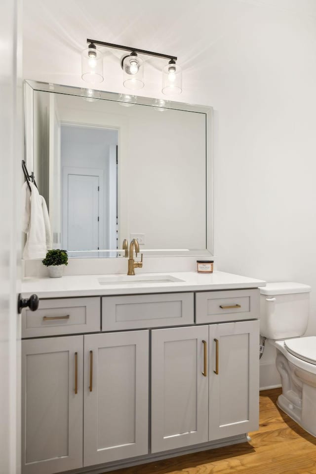 half bathroom featuring toilet, wood finished floors, and vanity