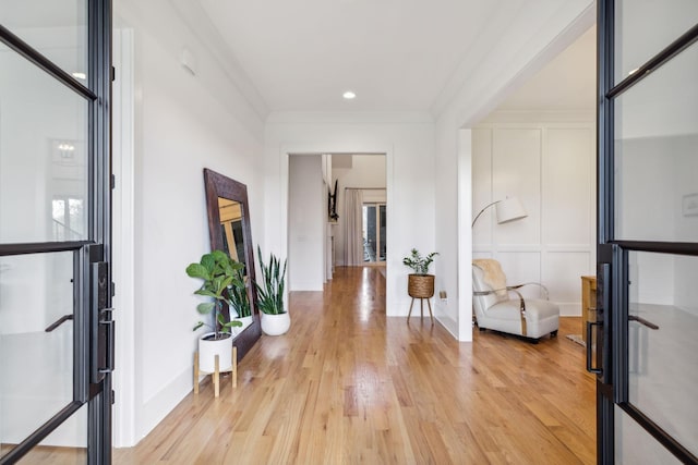 entryway featuring light wood finished floors, baseboards, and crown molding