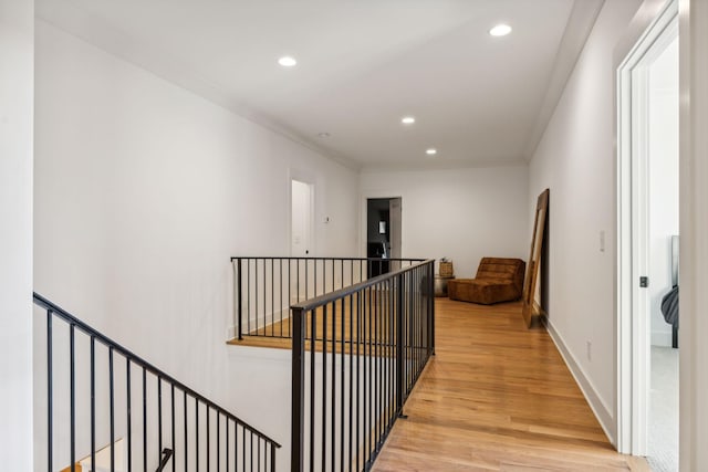 corridor with baseboards, recessed lighting, an upstairs landing, and light wood-style floors