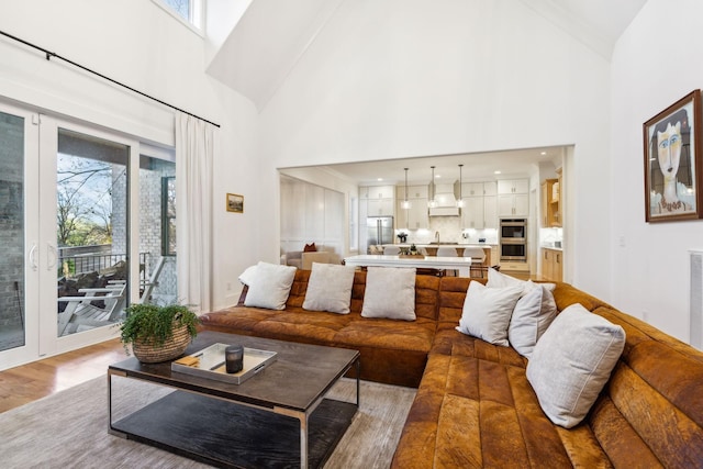 living room with light wood-style floors, visible vents, and high vaulted ceiling