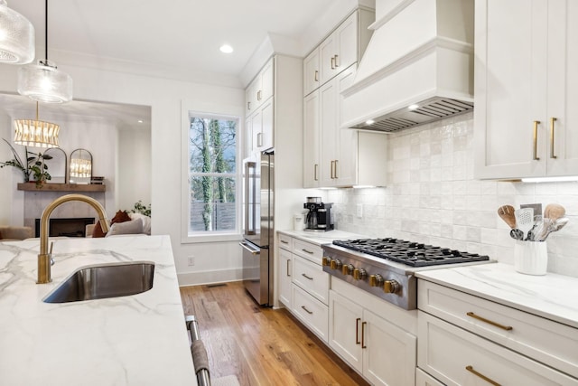 kitchen with custom exhaust hood, tasteful backsplash, appliances with stainless steel finishes, white cabinetry, and a sink