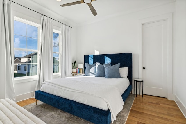 bedroom featuring a ceiling fan, baseboards, and wood finished floors