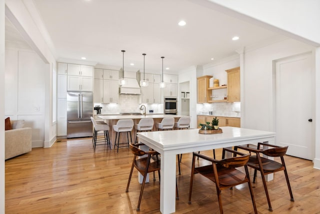 dining space featuring light wood finished floors, ornamental molding, baseboards, and recessed lighting