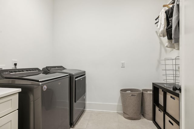 washroom featuring light tile patterned floors, independent washer and dryer, cabinet space, and baseboards