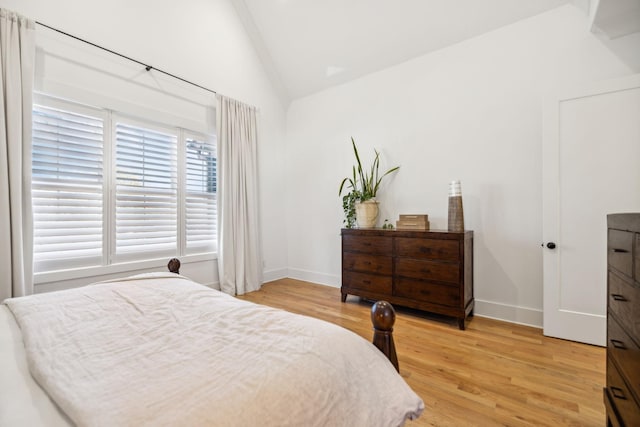 bedroom with lofted ceiling, baseboards, and light wood finished floors