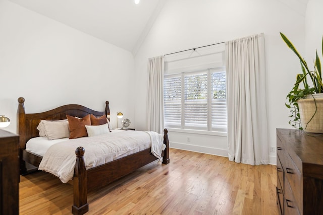 bedroom featuring vaulted ceiling, light wood-type flooring, and baseboards