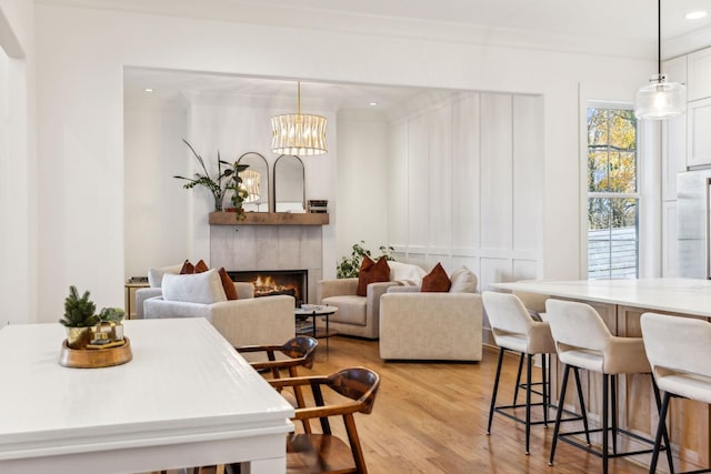 dining room featuring light wood-type flooring, a warm lit fireplace, crown molding, and recessed lighting