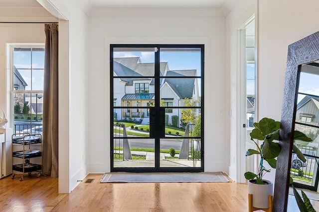 doorway to outside featuring visible vents, baseboards, and wood finished floors