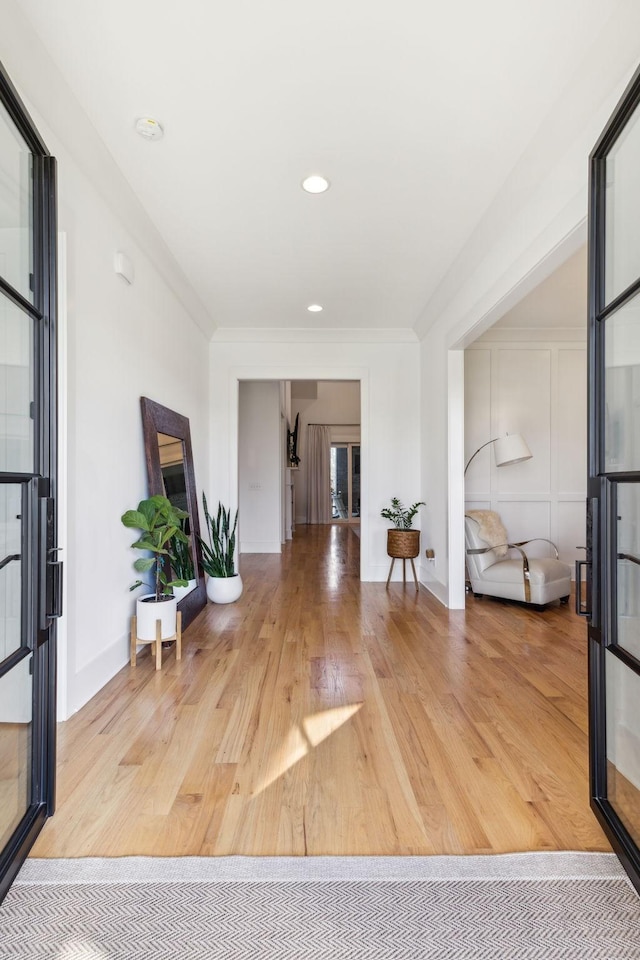 corridor with ornamental molding, french doors, baseboards, and wood finished floors