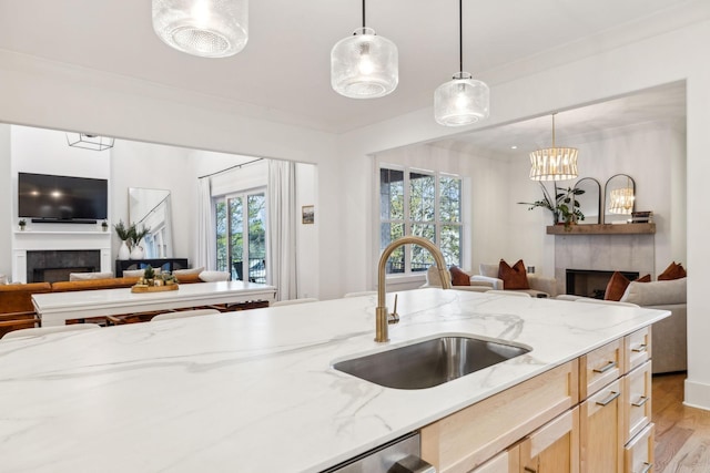 kitchen with open floor plan, light brown cabinetry, a tiled fireplace, and a sink