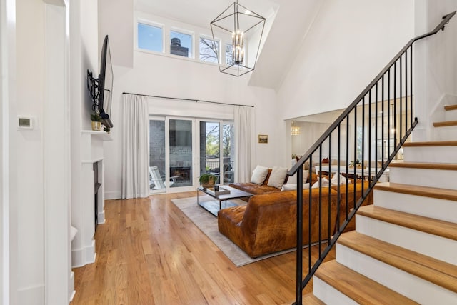 foyer featuring stairway, wood finished floors, an inviting chandelier, a high ceiling, and a fireplace