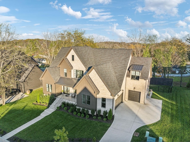 view of front of home with driveway, a front lawn, a standing seam roof, and roof with shingles