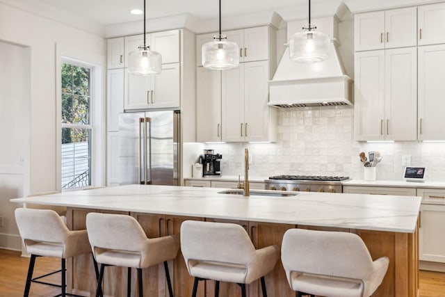 kitchen featuring decorative backsplash, light wood-type flooring, high quality fridge, and custom exhaust hood