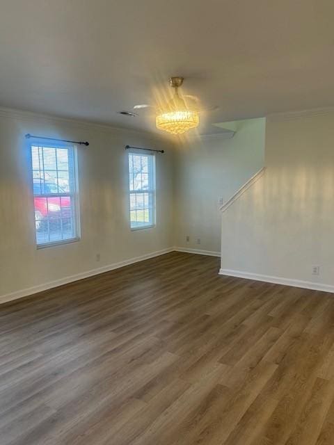 empty room with ornamental molding, wood finished floors, visible vents, and baseboards