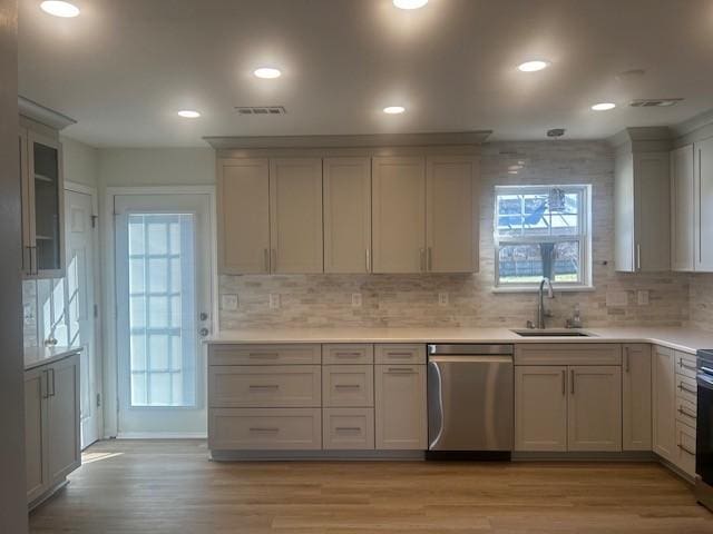 kitchen featuring a sink, light wood-style floors, light countertops, and stainless steel dishwasher