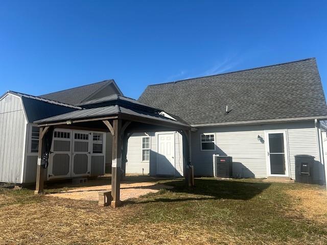 rear view of property with roof with shingles and a lawn