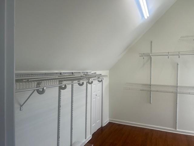 walk in closet with dark wood-style floors and vaulted ceiling