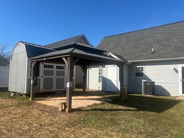 rear view of house featuring central AC unit, an outdoor structure, a yard, a gazebo, and a storage unit