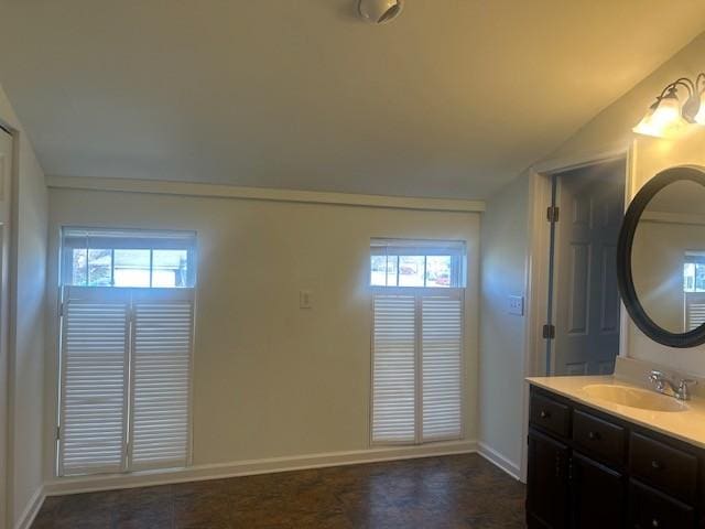 bathroom with lofted ceiling, vanity, and baseboards