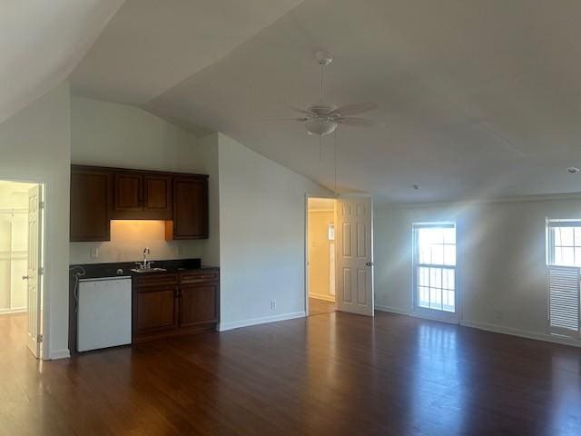 kitchen with dark countertops, dark wood-type flooring, open floor plan, a sink, and dishwasher