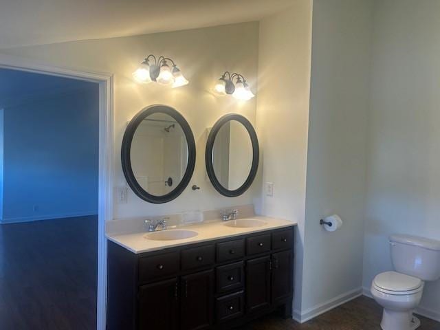 bathroom featuring toilet, double vanity, baseboards, and a sink