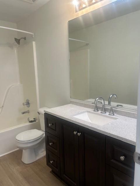 full bathroom featuring vanity, bathing tub / shower combination, wood finished floors, and toilet