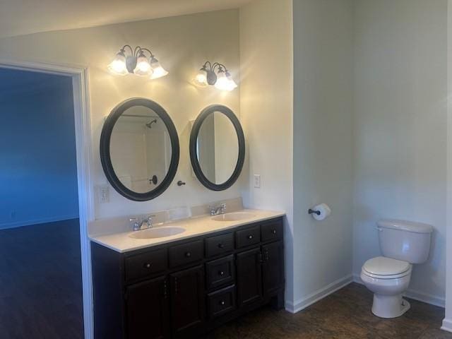 full bath with toilet, double vanity, baseboards, and a sink