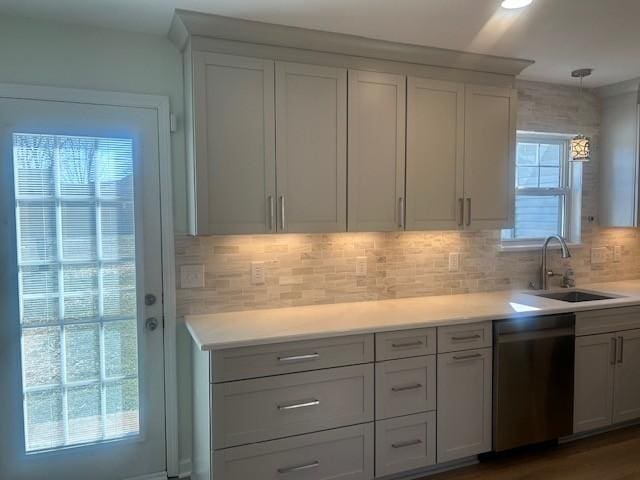 kitchen featuring a sink, backsplash, light countertops, and dishwasher