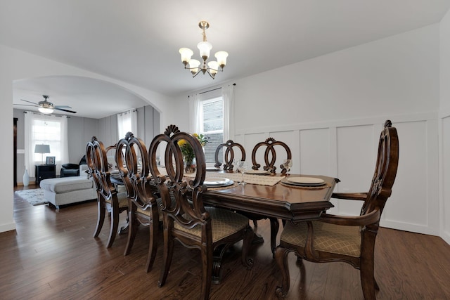 dining room featuring arched walkways, dark wood-type flooring, plenty of natural light, and a decorative wall