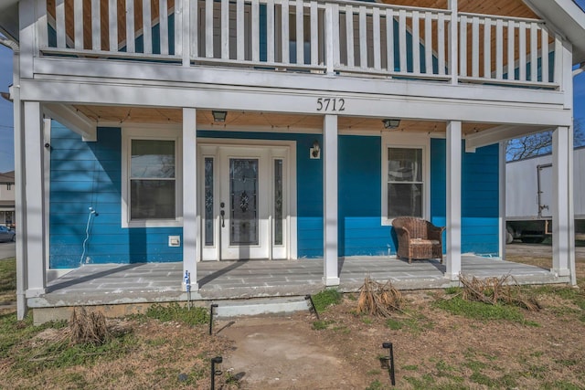 view of exterior entry featuring covered porch and a balcony